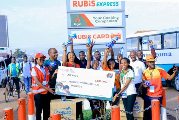 Rubis energy Uganda staff holding 5 million shillings cheque worth for AFRI pads with AFRI pads cartons on their feet | Rubis Energy Uganda partnership