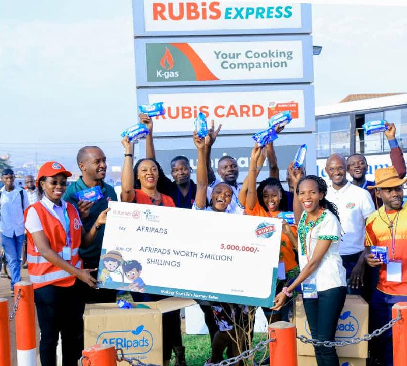 Rubis energy Uganda staff holding 5 million shillings cheque worth for AFRI pads with AFRI pads cartons on their feet | Rubis Energy Uganda partnership